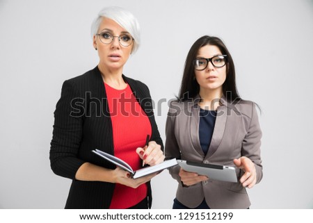 Portrait of two young girls with a tablet and a diary in their hands isolated on a light background