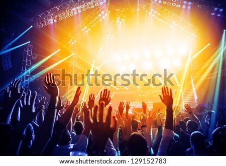 Photo of young people having fun at rock concert, active lifestyle, fans applauding to famous music band, nightlife, DJ on the stage in the club, crowd dancing on dance-floor, night performance Royalty-Free Stock Photo #129152783