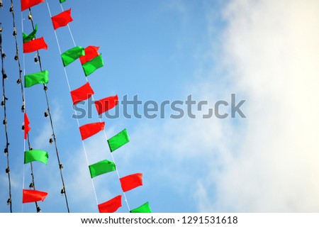 flag red green bunting on rope string vertical against blue sky cloud and light bulb line 