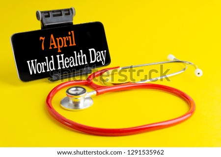 7 APRIL WORLD HEALTH DAY inscription written on mobile phone and stethoscope on yellow background with selective focus and crop fragment. Healthcare concept