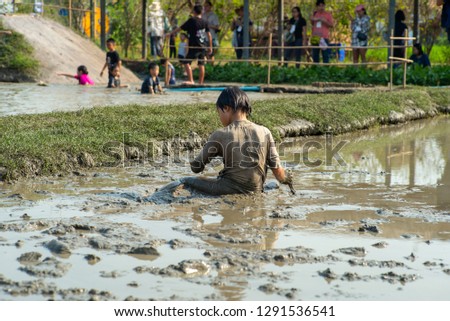 Portrait Asian wet girl enjoys plays in the mud pond and chases group of ducks in the farm.