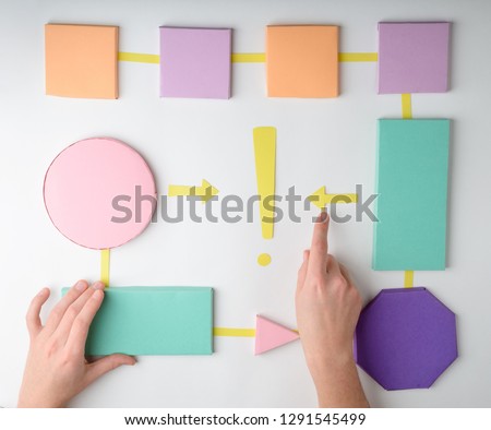 Hand making a paper flowchart, putting arrows between blocks. Algorithm of making decision concept.