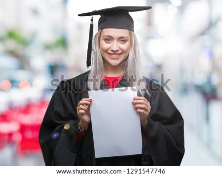 Young blonde woman wearing graduate uniform holding degree over isolated background with a happy face standing and smiling with a confident smile showing teeth