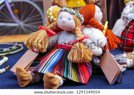 Colorful traditional dolls dressed with national Latvian, Lithuanian ornament dresses. Cozy handmade childhood dolls on the outside street market during city birthday days; nice souvenirs for tourist