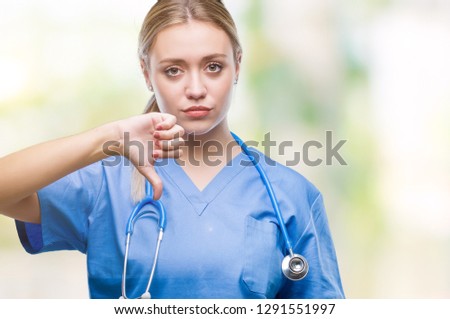 Young blonde surgeon doctor woman over isolated background looking unhappy and angry showing rejection and negative with thumbs down gesture. Bad expression.