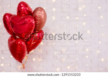 Valentine's day background - group of red heart shaped balloons over white wall with shiny lights