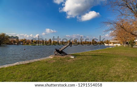 Autumn picture of a beautiful artificial Boating Lake at the heart of Szekesfehervar city,with an anchor monument in the foreground.
