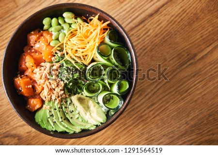 Top view of a poke bowl on wooden background with copy space. Traditional Hawaiian dish. Native Hawaiian and Japanese cuisine.