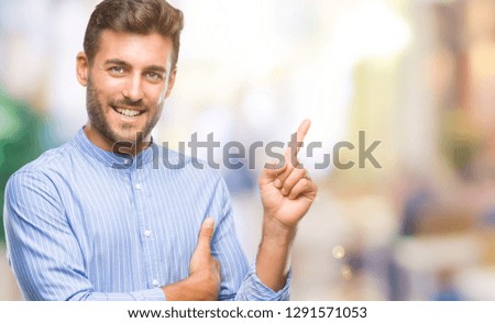Young handsome man over isolated background with a big smile on face, pointing with hand and finger to the side looking at the camera.