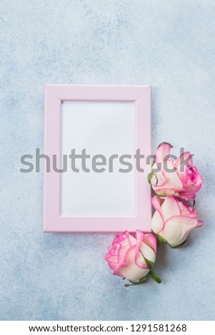 Creative minimalism flat lay with photo frame and pink roses on blue background. Valentines day, Mother and Spring concept. Mockup concept