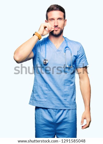 Handsome doctor man wearing medical uniform over isolated background mouth and lips shut as zip with fingers. Secret and silent, taboo talking