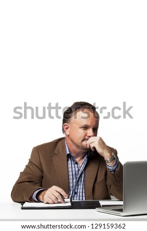 Mature businessman with hand on chin sitting at his desk