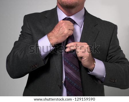 Close-up of a mature businessman in suit adjusting necktie