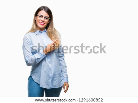 Young beautiful business woman wearing glasses over isolated background cheerful with a smile of face pointing with hand and finger up to the side with happy and natural expression on face