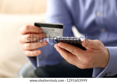 Male arms in suit hold credit card and phone make transfer closeup. Anti-fraud financial security when entering client discount program number or filling personal credential password login to account