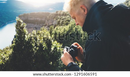 hipster tourist hold in hands taking photography click on retro vintage photo camera in auto, photographer looking on camera technology, blogger using hobby content, concept on panoramic landscape