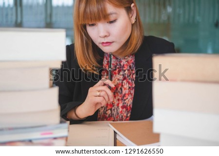Portrait of working woman sitting between a pile of books. This picture can be used in such concepts as business woman, librarian, financial, clerk, manager, office or reading.   