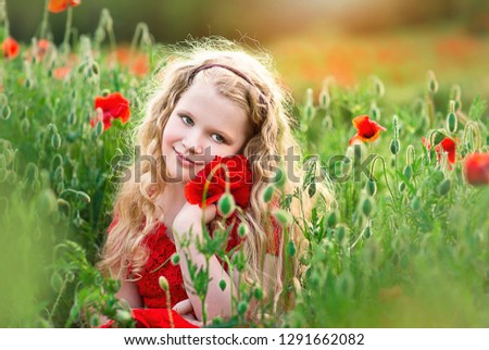 beautiful Blonde girl in poppy field. He enjoys the beauty and aromas.