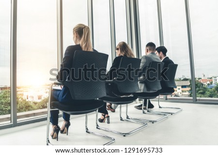 Businesswomen and businessmen waiting on chairs in office for job interview. Corporate business and human resources concept.