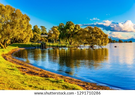  Fabulous summer sunset on lake Taupo. Lush clouds and blue sky are reflected in the smooth water of the lake. The concept of active and phototourism Royalty-Free Stock Photo #1291710286