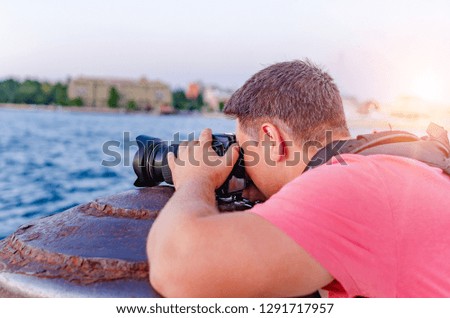 Man with camera photographing the sunset on the sea coast.