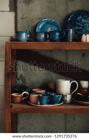 Colorful, white and blue ceramic cups and dishes on shelves of a pottery store