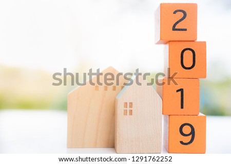 Wooden house with wood number 2019 on blurred green background and copy space for text using as background business, new year, real estate, property concept