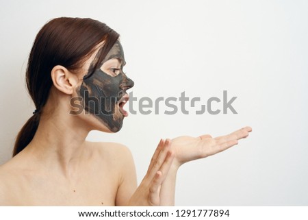 surprised woman in a cosmetic mask holds a free space on her hand