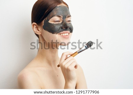 young woman in a cosmetic mask with makeup brush