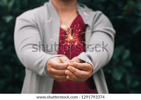 Woman hand holding fireworks and nature background. Party time.