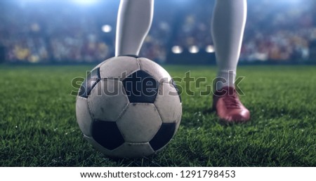 Photo of a soccer player, preparing a ball for a kick. Stadium and crowd are made in 3D.