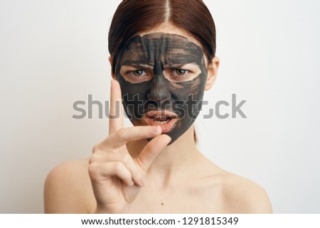 serious woman in a cosmetic mask lifting face skin