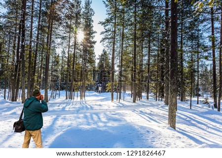 Lapland. Photographer in a green jacket takes pictures of a winter forest. The concept of extreme, active and phototourism