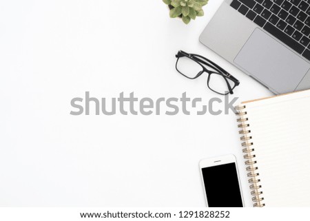 Creative flat lay photo of workspace desk. Top view office desk with laptop, glasses, phone, notebook and plant on white color background. Top view with copy space, flat lay photography.