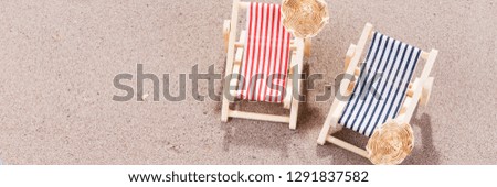 Two colorful sun loungers with hats on the sandy beach