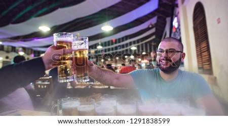 Two friends cheers or clink cold beer glasses draught beer at the bar