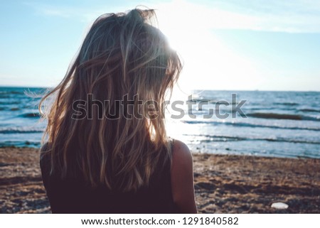 Girl looks on the sea. Dreary blonde girl looks at the sea. Sad for a loved one alone