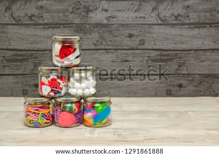 Glass jars filled with craft supplies with a shabby style black background