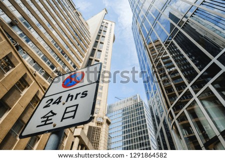 No Parking 24 hours Sign with chinese language surrounded by tall buildings in Hong Kong's business district.