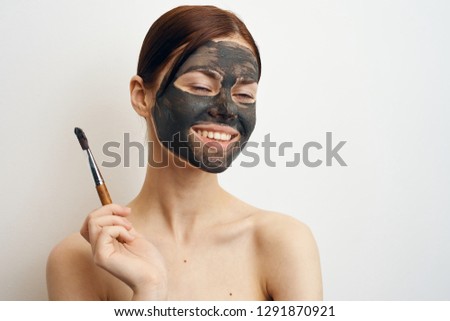 joyful woman with a cosmetic mask in hand makeup brush