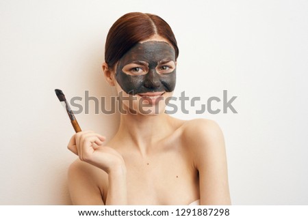 young woman in a cosmetic mask in hand makeup brush