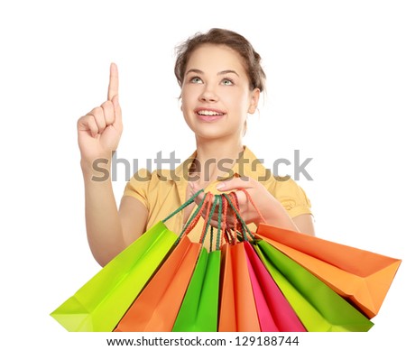 Young girl holding shopping bag and pointing up , isolated on white background