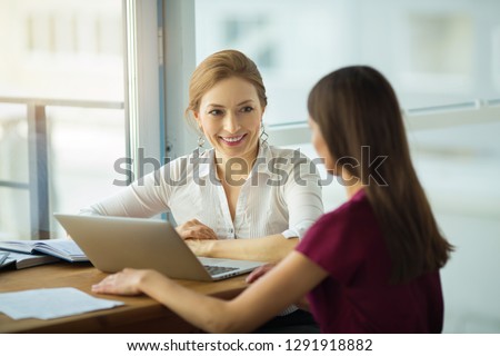 beautiful young woman with a smile communicates with a woman at work in the office Royalty-Free Stock Photo #1291918882