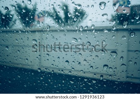 A rainy day view through the car windows with rain drops. Blurred background with rain drops on glass. Image contains certain grain, noise and soft focus. 