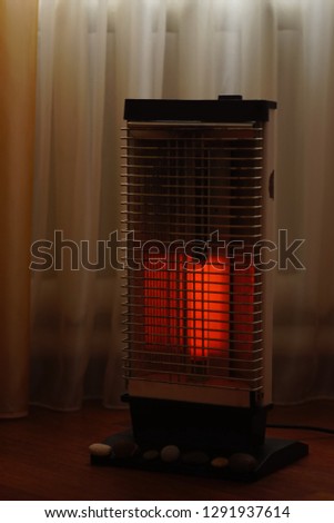 Vintage electric heater Ugolek with a burning lamp closeup. Selective focus.