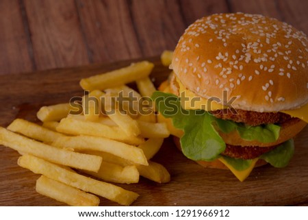 Homemade hamburger on a wooden tray with french fries. Delicious sandwich hamburger with meat or pork ham cheese and fresh vegetable. Hamburger or sandwich is the popular fast food for brunch or lunch