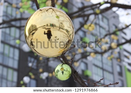 silhouette of a man in the reflection of the Christmas ball. the tree is decorated for the new year against the background of the year, a modern multi-storey multi-colored building