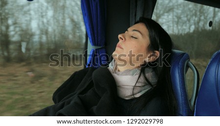 Woman passenger asleep at bus while traveling on road. Girl sleeping next to bus window
