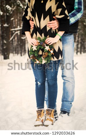 Beautiful couple embracing their love in snow, he hold her while standing in back