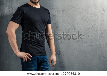 Young healthy man with black T-shirt on concrete background with copyspace for your text. Picture without model face.